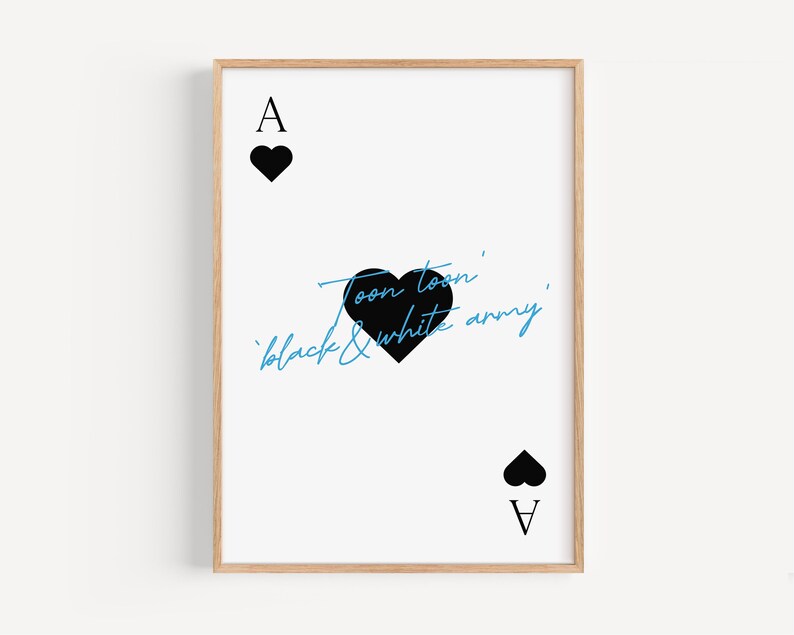 May include: A framed print featuring the Ace of Hearts playing card design. The card has a white background with black heart symbols and the text "Toon toon' black & white army" in black and blue script.