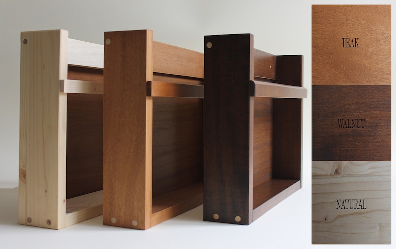 May include: Three wooden shelves in natural, teak, and walnut finishes. The shelves have a simple design with two shelves and a small lip on the top shelf. The shelves are made of solid wood and have a natural finish. The shelves are shown against a white background.