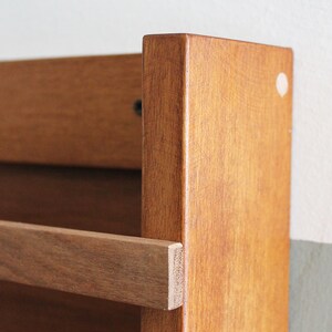 May include: A wooden wall-mounted shelf with a single brown wooden shelf. The shelf is made of solid wood and has a natural finish.