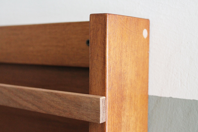 May include: A wooden wall-mounted shelf with a single brown wooden shelf. The shelf is made of solid wood and has a natural finish.