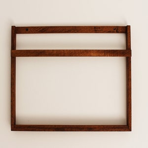May include: A dark brown wooden wall shelf with two shelves. The shelf is mounted on a white wall. The shelf has a label that says "Bix Design".