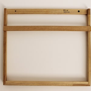 May include: A wooden wall shelf with two shelves. The shelf is made of natural wood and has a simple, minimalist design. The shelf is labeled "Bix Design".