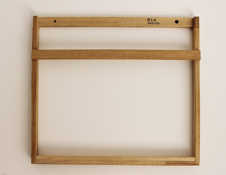 May include: A wooden wall shelf with two shelves. The shelf is made of natural wood and has a simple, minimalist design. The shelf is labeled "Bix Design".