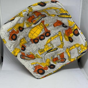 May include: A gray and white fabric bowl with a construction vehicle print. The bowl features yellow and orange construction vehicles, including excavators, dump trucks, and cement mixers.