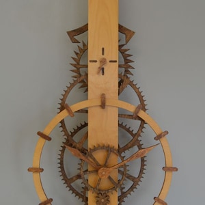 May include: Wooden wall clock with a light brown vertical base and a series of dark brown gears and a circular frame. The clock hands are made of wood. The clock has a pendulum at the bottom.