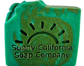 May include: A green bar of soap with a swirl pattern and a sun design. The soap is labeled "Sunny California Soap Company".