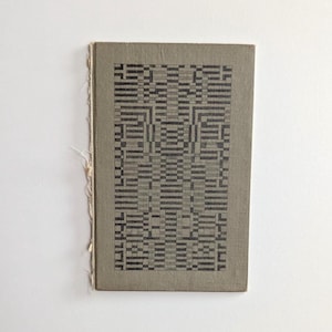 May include: A vintage book with a green linen cover and a black and white geometric pattern.