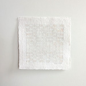 May include: A white grid pattern drawn on a textured paper with a signature in the bottom right corner.
