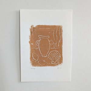 May include: A brown and white linocut print depicting a still life scene. The print shows a vase, seashells, and abstract forms on a textured backdrop. The artwork is signed and dated.