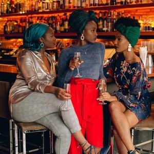 three girls at a bar wearing statement earrings with champagne glasses in hand