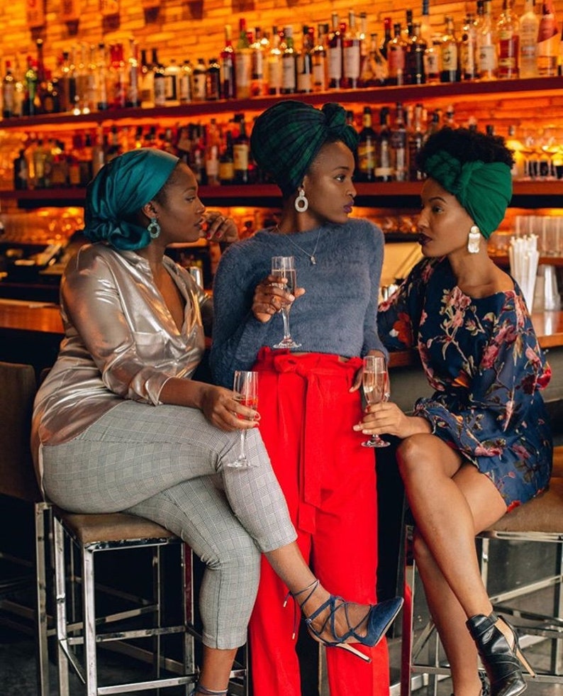 three girls at a bar wearing statement earrings with champagne glasses in hand