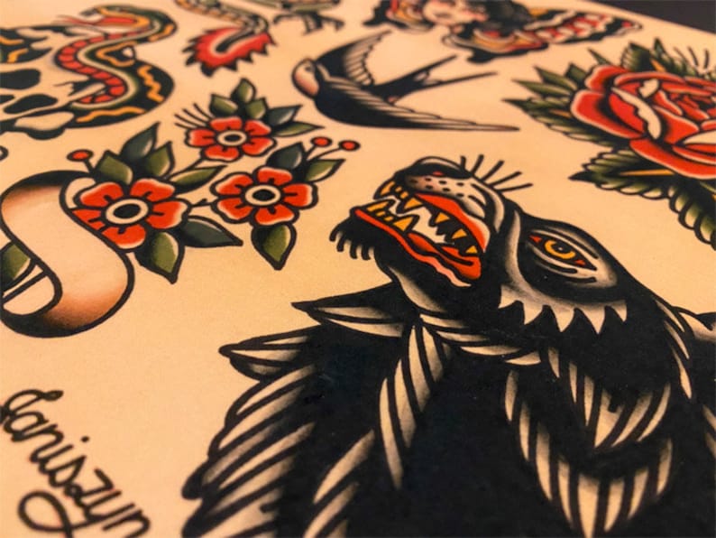 May include: A traditional tattoo flash sheet with a black wolf head, a red rose, a swallow, a skull with a snake, and a banner with the text "Unison".