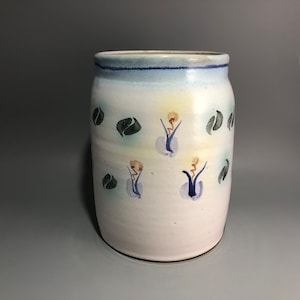 May include: White ceramic vase with a blue and green glaze. The vase has a floral design with blue, green, and yellow accents.