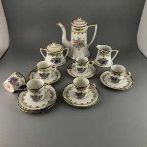 May include: A vintage porcelain tea set with floral designs in shades of pink, purple, and yellow. The set includes a teapot, creamer, sugar bowl, and six cups and saucers.