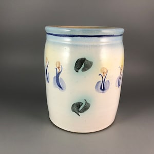 May include: White ceramic jar with a blue rim and hand-painted blue and green floral designs.
