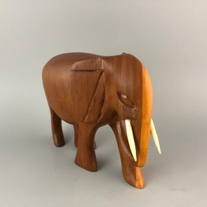 May include: A wooden elephant figurine with carved details and ivory tusks. The elephant is standing on all four legs and has a realistic appearance.
