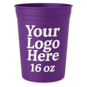 May include: A purple plastic cup with the text "Your Logo Here" in white. The cup is labeled "16 oz". The cup is cylindrical with a slightly flared top. Ideal for promotional events or personalized gifts.