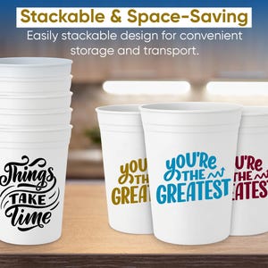 May include: White stackable plastic cups with various phrases printed on them, including "Things Take Time" in black, and "You're the Greatest" in blue. The cups are designed for convenient storage.