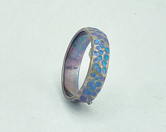 Titanium ring electric blue coloured, with a hammered surface .