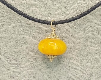 Amber bead pendant, with antique style flower terminals, in 9 K gold