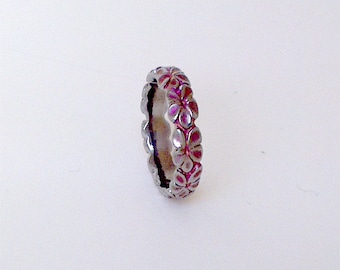 Titanium Flower Ring, an intricately carved row of flowers . In Titanium, coloured pink