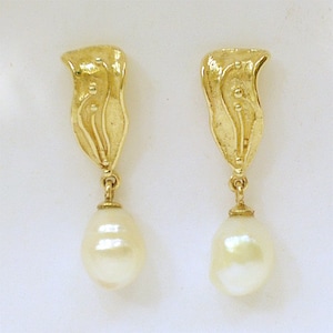 May include: A pair of gold earrings with a leaf-shaped top and a dangling, pear-shaped pearl. The earrings have a polished finish and a warm, yellow colour. The design is suitable for formal events and special occasions.