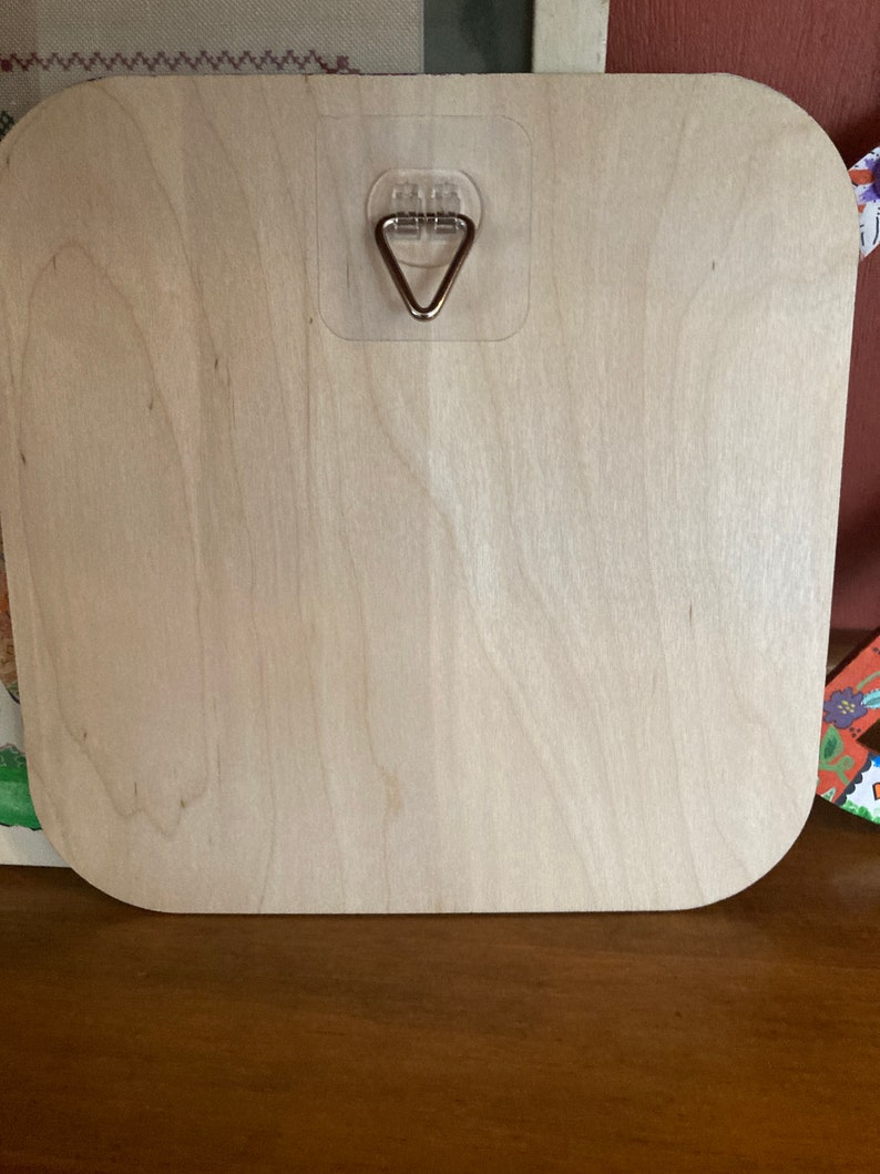 May include: A light wood square sign with rounded corners. The sign has a clear plastic hook attached to the back.