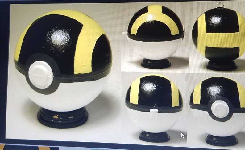 May include: A white, black, and yellow Pokeball with a black base. The Pokeball is painted with a yellow H on the top and a yellow ring around the middle. The Pokeball is shown from multiple angles.