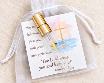 May include: A small clear glass vial with a gold cap and a gold cross charm inside, resting on a white card featuring a watercolor cross illustration and the text May this holy water bless you with peace and protection. The Lord bless you and keep you! Numbers 6:24. Set of 6.