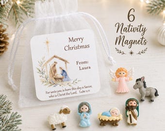 May include: A set of six Nativity magnets in a white organza drawstring bag with a tag reading Merry Christmas From: Laura and a Bible verse. The magnets include a pink angel, a gray donkey, a white sheep, a blue figure, a baby in a manger, and a man.