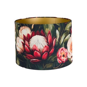 May include: A black and green lampshade with a gold interior features a floral print of red and white proteas and pink peonies.