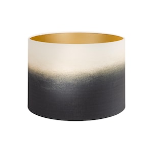 May include: A white and black ombre lampshade with a gold interior. The lampshade is cylindrical and has a textured finish.