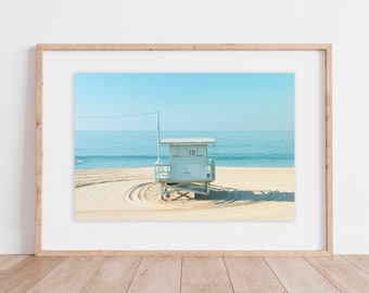 May include: A white lifeguard stand with the number "10" on the side, situated on a sandy beach with blue ocean waves in the background.