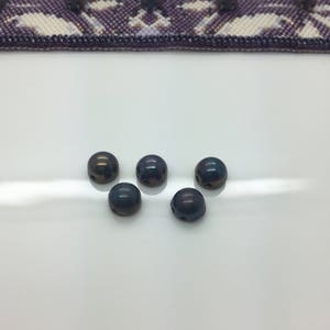 May include: Six iridescent black dome-shaped buttons with two holes each.