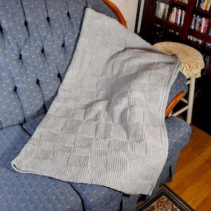 May include: A light blue crocheted blanket with a waffle stitch pattern, draped over a blue armchair.