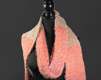 May include: A soft, fuzzy scarf with a gradient of pink and beige colors. The scarf is draped over a black mannequin.