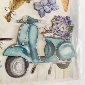 May include: Decorative stickers featuring a teal scooter carrying a bouquet of blue hydrangeas. Other stickers include pink and purple flowers, and a flower-shaped ice cream cone. The stickers have a watercolor effect.