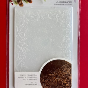 May include: A clear plastic 3D embossing folder by Crafter's Companion labeled Pretty Poinsettia. The folder features a decorative border of poinsettia flowers and holly leaves with a dotted background. It measures 5 inches by 7 inches.