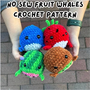 May include: Four crocheted fruit whale plushies. A blue whale, a red strawberry whale, a green watermelon whale, and a brown chocolate whale.