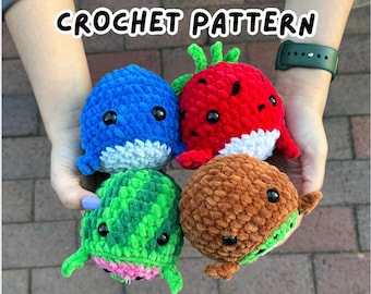 May include: Four crocheted fruit whale plushies. A blue whale, a red strawberry whale, a green watermelon whale, and a brown chocolate whale.