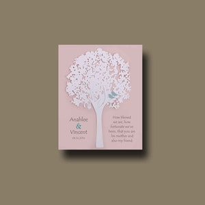 May include: A white papercut tree with two blue birds perched on a branch. The tree is on a pink background with the text "Anahlee & Vincent 06.14.2014" and a quote about how blessed the couple is to have the person in their lives.