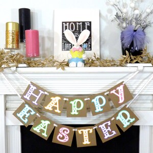 May include: A festive Easter banner with the words "HAPPY EASTER" in colorful letters hangs over a fireplace. The mantel is decorated with candles, a bunny figurine, and a framed sign that reads "HOME IS LOVE HERE".