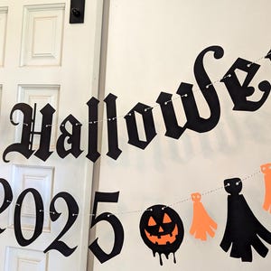 May include: A Halloween banner with the words "Happy Halloween 2025" in black gothic lettering. The banner includes orange and black decorative cutouts of pumpkins and ghosts, strung on a white string, perfect for Halloween decorations.