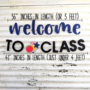 Może przedstawiać: Baner klasowy z napisem "welcome TO CLASS" w kolorze granatowym i czarnym. G&oacute;rny baner ma 91 cm długości, a dolny 104 cm. Baner zawiera czerwone jabłko, ż&oacute;łty oł&oacute;wek i niebieską gwiazdę.