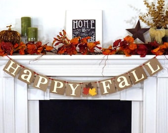 May include: A festive fall mantel display with a banner that reads "HAPPY FALL." The mantel is decorated with autumn leaves, a pumpkin, candles, and a framed sign that says "HOME is where the heart is."