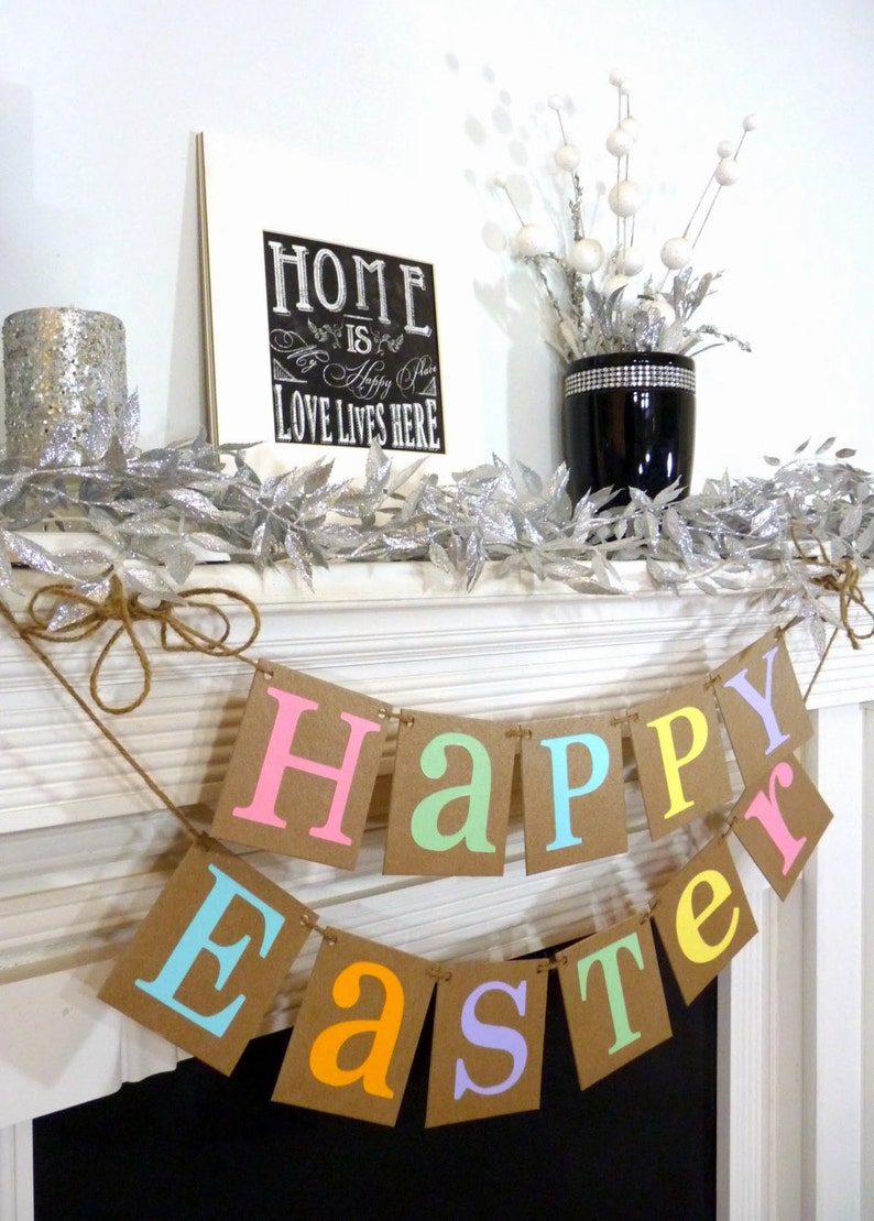 May include: A festive Easter banner with the words "Happy Easter" in pastel colors. The banner is strung on twine and hangs in front of a white fireplace. A framed sign with the text "Home is Happy Place, Love Lives Here" is visible.