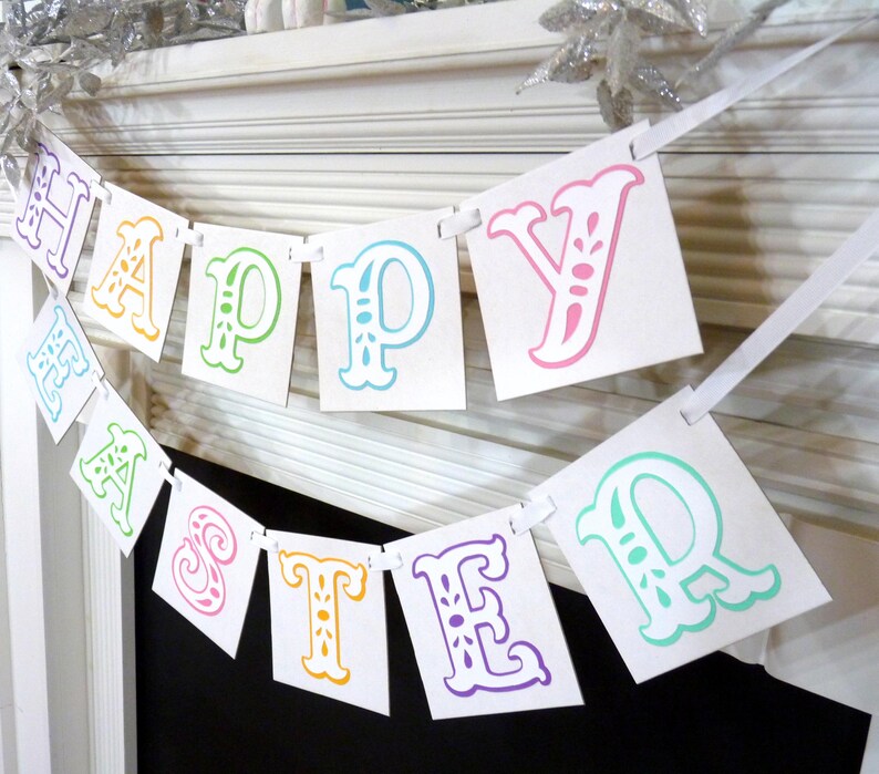 May include: A white banner with the words "HAPPY EASTER" printed in colorful, ornate letters. The letters are in shades of purple, yellow, green, and pink. The banner is strung on a white ribbon, perfect for Easter decorations.