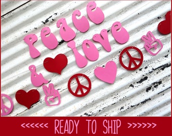 May include: A pink and red paper banner with the word "LOVE", peace signs, and hearts. The banner is strung on a thin string and is set against a white, textured background. The text "READY TO SHIP" is at the bottom.