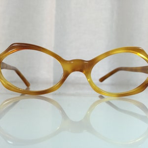 May include: A pair of tortoise shell eyeglasses with oval lenses. The glasses are on a white surface and are reflected in the surface.