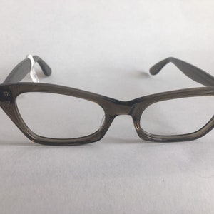 May include: Brown cat-eye glasses with clear lenses and gold star accents on the temples.